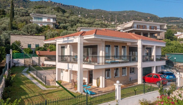 εξοχική ισόγεια κατοικία σε κήπο με γκαζόν με θέα θάλασσα και καταπράσινο λόφο
